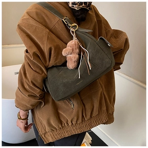 Detail of dark green suede half-moon bag with cute brown plush bear charm and gold hardware