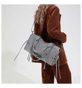 Detail showing the gray distressed texture, side straps and tassels of a moto tote bag