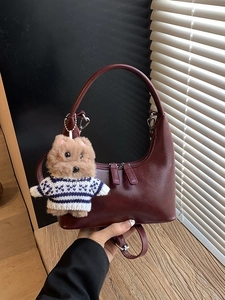 Sac bandoulière vintage bordeaux en demi-lune avec pendentif chien sur table en bois