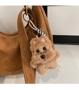 Dettaglio di un ciondolo per cani in peluche marrone con targhetta TOP DOG su una borsa