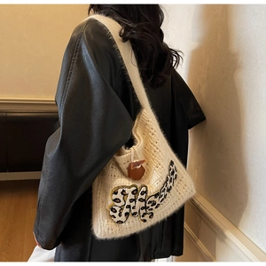 Detail of cream knit shoulder bag featuring leopard print M patch and leather pendant