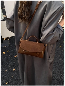 Brown leather handbag with gold hardware styled on model in autumn outdoor setting