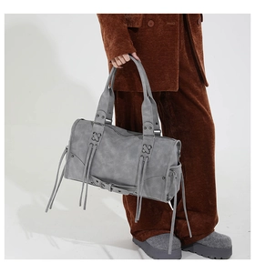 Macro view of vintage gray tote bag with long tassels, metal rivets, and belt details