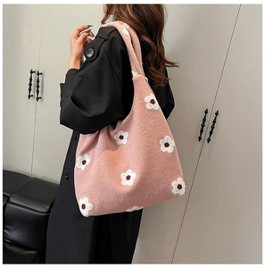 Detailed close-up of pink plush tote bag with white floral embroidery and wide strap