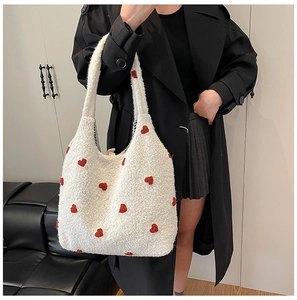 Detail of plush cream tote bag featuring red heart embroidery on soft faux fur material