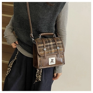 Close-up of British plaid wool texture and cute bear patch on the vintage leather backpack