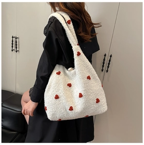Detailed close-up of plush white tote bag with red heart embroidery on model shoulder