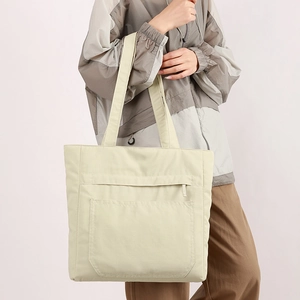 Detailed shoulder view of a light nylon tote bag with front zipper pocket and large capacity