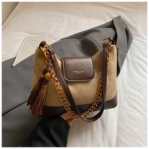 Detail of suede shoulder bag with gold chain and fringe tassel in a winter setting