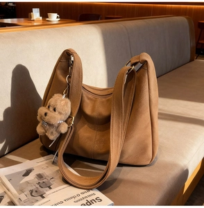 Primo piano di una borsa hobo in pelle marrone con un simpatico ciondolo a cucciolo