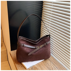 Close-up of deep brown suede tote bag featuring leather belt straps and golden buckles