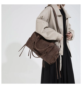 Close-up of brown suede tote bag featuring adjustable metal eyelets and long tassels