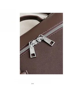 Detail shot of the dual silver zippers on a dark brown textured leather shoulder bag