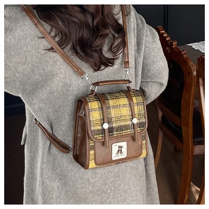 Détail du sac à dos à carreaux style anglais porté sur un manteau gris en laine douce