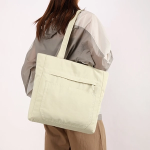 Nylon tote bag detail with wide shoulder strap and waterproof front zipper pocket