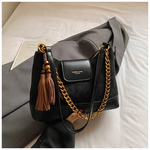 Close-up of black mixed-material shoulder bag with gold chain and beaded tassel detail