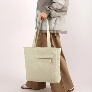 Detail of beige nylon tote bag with functional zipper pockets and versatile shoulder straps