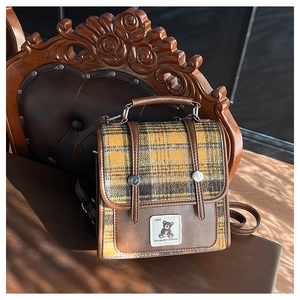 Detailed view of British style plaid backpack with bear embroidery on vintage chair