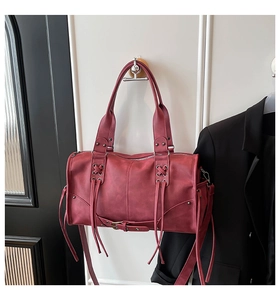 Detail of burgundy Boston bag with vintage lace-up straps and metal ring accents