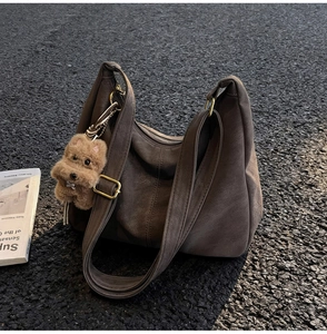 Dettaglio borsa hobo in pelle scamosciata marrone scuro con fibbia dorata e ciondolo orso