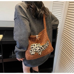 Close-up of brown knit tote bag with leopard print M patch and toggle closure