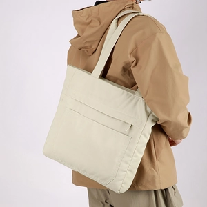 Close-up of beige waterproof tote bag showing functional pockets and nylon texture