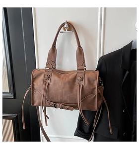 Detail of vintage brown leather Boston bag featuring lace-up straps and long fringes