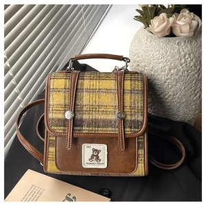 Detailed view of British plaid fabric and PU leather trim with a bear embroidery patch
