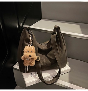 Dettaglio della borsa hobo in camoscio marrone scuro con fibbia e ciondolo a orso