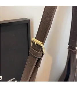 Detail of adjustable dark brown faux leather shoulder strap with gold metal buckle