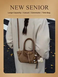 Detail of dark coffee suede tote bag with leather straps and decorative puppy charm