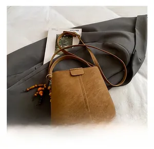 Détails du sac seau marron avec breloque en perles de bois et pieds de protection en métal