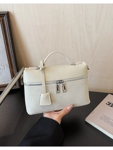 Detail of beige litchi grain leather handbag with silver double zippers and top handle
