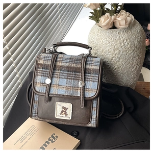 Close-up of vintage British plaid backpack with leather trim and bear embroidery patch