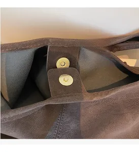 Close-up of magnetic snap closure on brown vintage tote bag with gold-tone hardware