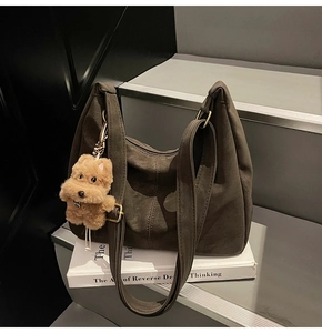 Dettaglio borsa hobo in camoscio verde oliva con ciondolo a orso su scale grigie