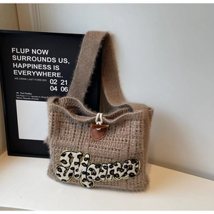 Close-up of brown knit tote bag with leopard MAMA patch and wooden horn buckle closure