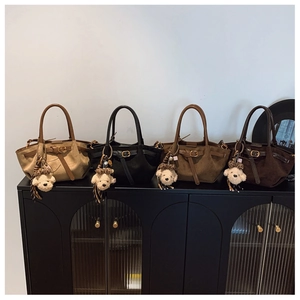 Detail of four faux suede handbags in beige and brown with cute teddy bear charms
