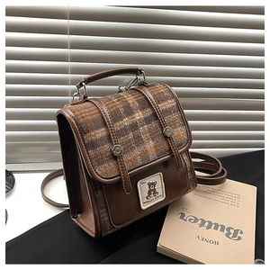 Detailed view of the plaid wool flap and premium brown leather texture of the retro backpack