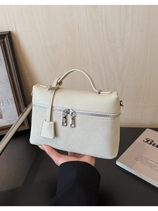 Detail of cream white leather handbag with dual zippers and textured lychee pattern