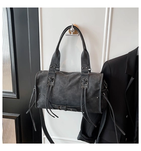 Close-up of distressed leather motorcycle tote bag with metallic eyelets and long tassels