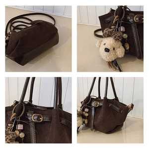 Detail view of suede tote with plush dog charm and polished leather strap accents