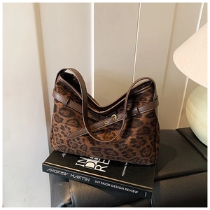 Detail of leopard print suede underarm bag featuring brown leather trim and golden buckle