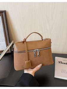 Detail view of large brown textured leather handbag featuring unique dual zipper closure