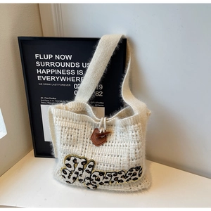 Detail of knitted tote bag with leopard print embroidery and leather horn buckle closure