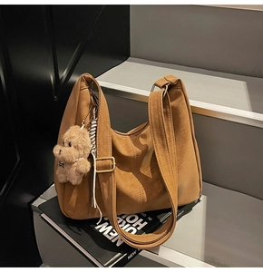 Dettaglio della borsa a mezzaluna in pelle PU marrone con ciondolo a forma di cane