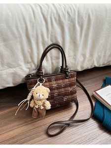 Detailed view of a brown plaid bucket bag with a cute bear pendant and leather handles