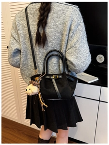Detail of black suede shoulder bag with gold buckle and cute plush dog charm