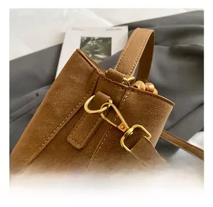Détail du crochet en métal doré et du cuir à motif litchi du sac seau marron élégant