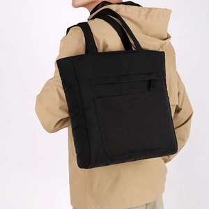 Rear view of a model carrying a large black waterproof nylon tote bag with exterior pockets
